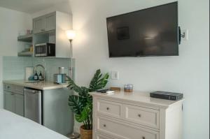 a room with a tv on the wall and a kitchen at Walkable to Beach, Restaurants & Shops. Remodeled! in Wailea