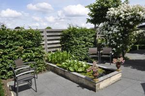 un jardín con 2 sillas y un jardín de flores en B&B De Edelsteen en Zutendaal