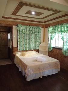 a bedroom with a bed with green curtains and a window at Greenviews Resort & Restaurant Port Barton in San Vicente