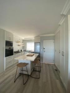a kitchen with a white island and stools at 42 Whale Rock Estate in Hermanus +3 photos