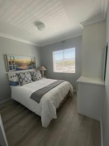 a bedroom with a large bed and a window at 42 Whale Rock Estate in Hermanus