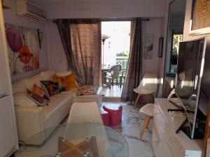 ein Wohnzimmer mit einem weißen Sofa und einem TV in der Unterkunft Sole e Mare 2 pièces aperçu mer in Golfe-Juan