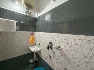 La salle de bains est pourvue d'un lavabo et d'un mur carrelé. dans l'établissement Anjali HOMESTAY, à Siliguri