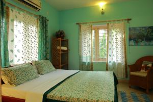 a bedroom with a bed with blue walls and windows at Bella Homestay Kerala in Alleppey