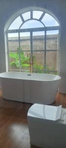a bathroom with a tub and a window and a toilet at Villa Nducha in Dar es Salaam