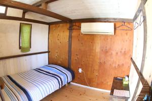 a bedroom with a bed in a room with wooden walls at Haryugetu Guesthouse in NASA in Kaiyo