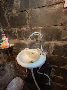 a bathroom with a sink in a brick wall at Sainj Riverside Cottages in Sainj