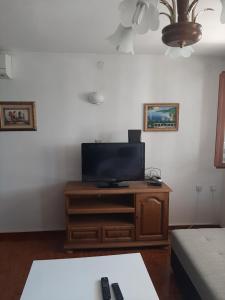 sala de estar con TV de pantalla plana en un centro de entretenimiento de madera en Apartments Kalsan, en Novalja