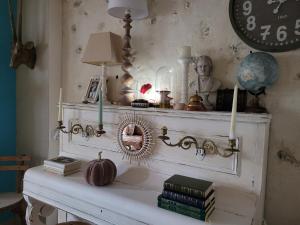 einen Kamin mit einem Regal mit Büchern und einer Uhr in der Unterkunft Maison féérique et ludique, avec jeux de piste in Saint-Romain-le-Preux