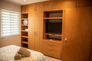 a bedroom with a television in a wooden cabinet at Downtown Beach Condo w/ Pool in Cabo San Lucas