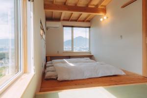 a bed in a room with a large window at Cider Barn &more in Iida