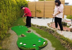 dwoje ludzi grających w golfa na sztucznym polu golfowym w obiekcie Hananoyado Yumefuji w mieście Fujikawaguchiko