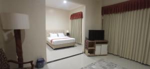 a hotel room with a bed and a television at Djembar Inn in Kalasan
