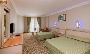 a hotel room with two beds and a television at Holiday Park Resort in Okurcalar
