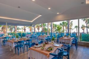 a restaurant with tables and chairs and palm trees at Holiday Park Resort - Ultra All İnclusive in Okurcalar