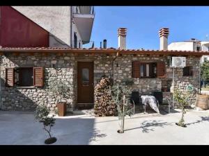 a stone house with a table and chairs in front of it at Το πατρικό του Σταύρου. in Mouzákion