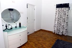 La salle de bains est pourvue d'un lavabo et d'un miroir sur une commode. dans l'établissement HAILSTONE HOME STAY, à Ooty