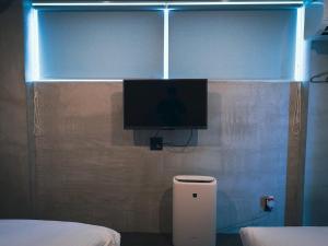 einen TV an der Wand in einem Zimmer mit einem Bett in der Unterkunft maejima Hotel in Naha