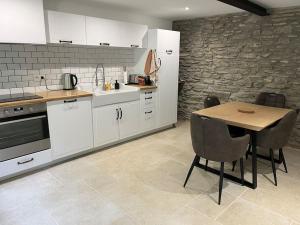 a kitchen with white cabinets and a table with chairs at Joly Cottage in Corbion