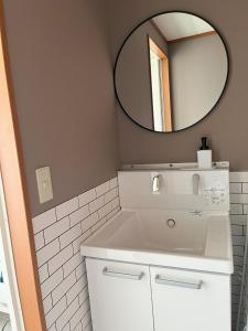 La salle de bains est pourvue d'un lavabo blanc et d'un miroir. dans l'établissement Shell Beach Hamanako - Vacation STAY 14730, à Hamamatsu