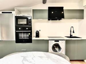 eine Küche mit einer Waschmaschine und einer Mikrowelle in der Unterkunft Cannes appartement 2 chambres - 19JDR in Cannes
