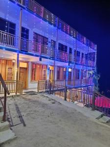 a building with christmas lights on the side of it at Great Himalayan Nature View Resort in Banjār