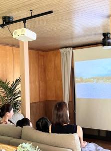 un groupe de personnes assises sur un canapé en regardant une présentation dans l'établissement Shell Beach Hamanako - Vacation STAY 14730, à Hamamatsu