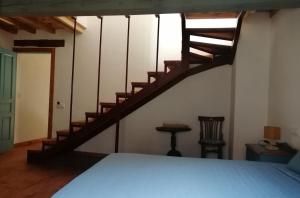 a bedroom with a bed and a wooden staircase at Casas Rurales Casas en Batuecas in Villanueva del Conde