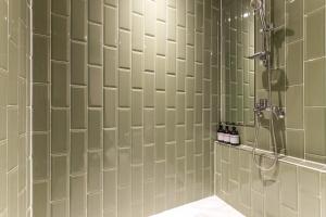 a bathroom with a shower with green tiled walls at Brown Dot Hotel Incheon Jakjeon in Incheon