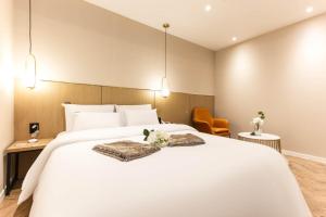 1 dormitorio con 1 cama blanca grande y 2 sillas en Brown Dot Hotel Incheon Jakjeon en Incheon