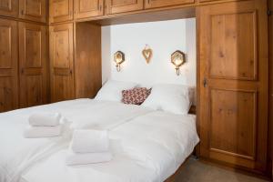 sypialnia z białym łóżkiem i drewnianymi szafkami w obiekcie Ferienwohnung für 5 Personen Bot La Pala Lenzerheide w mieście Lenzerheide