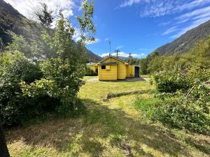 una casa amarilla en un campo con montañas en el fondo en Basic, Super 'Cosy' Cabin in The Middle of National Park and Mountains, en Otira