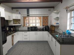 a kitchen with white cabinets and a sink at Maisha@Toti in Amanzimtoti