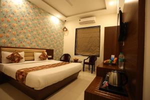 a hotel room with a bed and a desk and a table at Hotel Bhairav Bagh with Swimming Pool in Udaipur