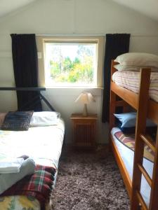 Zimmer mit 2 Etagenbetten und einem Fenster in der Unterkunft Rustic, Basic Cosy Alpine Hut, in the middle of the Mountains in Otira