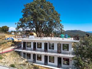 Atithi Home Stay - Himalayas view في Chaukori: مبنى أبيض عليه شجرة