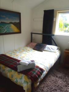 1 cama en un dormitorio con una pintura en la pared en Rustic, Basic Cosy Alpine Hut, in the middle of the Mountains, en Otira