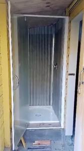 een glazen deur van een douche in de kamer bij Rustic, Basic Cosy Alpine Hut, in the middle of the Mountains in Otira