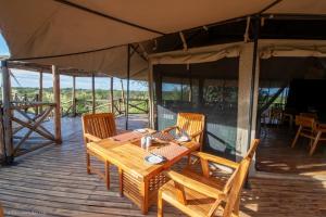 a wooden table and chairs on a wooden deck at Serengeti Kifaru Tented Lodge in Mugumu +53 photos