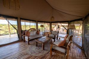 Mugumu的住宿－Serengeti Kifaru Tented Lodge，帐篷内的客厅配有椅子和桌子
