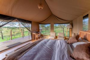 a bedroom with a large bed and a large window at Serengeti Kifaru Tented Lodge in Mugumu