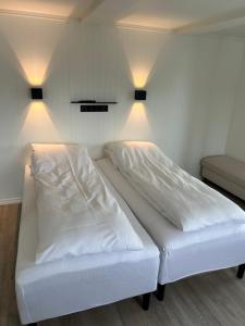 Finsnes Gaard في فينسنس: سرير أبيض في غرفة بها مصباحين