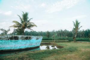 a blue boat in a field with palm trees at Umadesa villa in Penginyahan