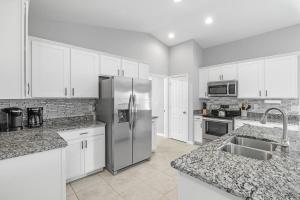 a kitchen with a stainless steel refrigerator and white cabinets at The Cape Escape Pet-Friendly Sleeps 7 in Cape Coral