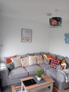 a living room with a gray couch with colorful pillows at J16 Mablethorpe Pet Friendly Chalet in Mablethorpe