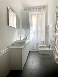 un bagno bianco con due lavandini, una vasca e una finestra di Studio61 - centro storico a Ivrea