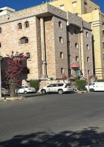 two cars parked in front of a large building at فندق روتانة الفرسان بالحمرا in Jeddah