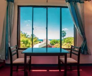 einen Tisch und Stühle vor einem großen Fenster in der Unterkunft That's Why Beach Cabanas Nilaveli in Nilaveli