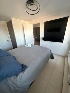 a bedroom with a bed and a flat screen tv at Gran Vista al Mar Moderno Depto Costa Montemar in Concón