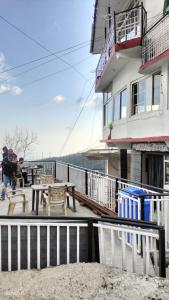 un edificio con una mesa y bancos en un balcón en Heena Guest House, en Dharamshala
